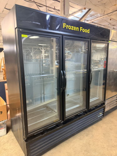TRUE THREE-DOOR GLASS DISPLAY FREEZER WITH THREE HINGED GLASS DOORS, INTERIOR LED LIGHTING, ADJUSTABLE COATED WIRE SHELVING, BOTTOM-MOUNT DUAL COMPRESSOR REFRIGERATION SYSTEM, AND BLACK EXTERIOR FINISH.