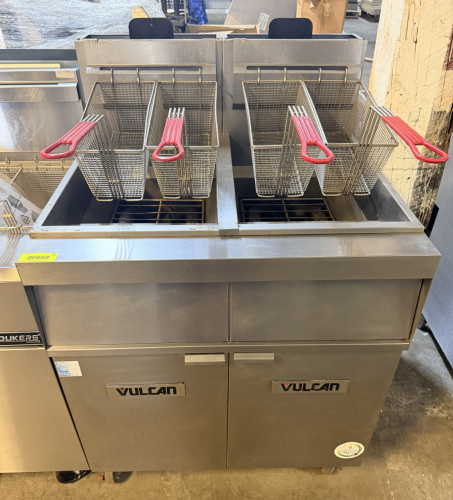 VULCAN TWIN-BATTERY FLOOR FRYER SYSTEM WITH TWO FRY POTS, FOUR FRY BASKETS WITH COATED HANDLES, STAINLESS STEEL CABINET CONSTRUCTION, INTEGRATED FILTRATION SYSTEM, DRAIN ASSEMBLY, RINSE/FILL HOSE CONNECTION, INDIVIDUAL TEMPERATURE CONTROLS, AND CASTERS.