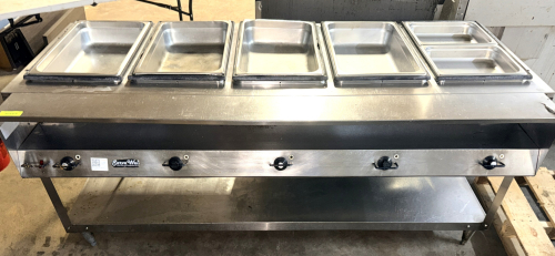 SERVEWELL FIVE-WELL STEAM TABLE / HOT FOOD SERVING TABLE WITH STAINLESS STEEL CONSTRUCTION, INDIVIDUAL WELL CONTROLS, LOWER STORAGE SHELF, CASTERS, AND ASSORTED STAINLESS STEEL FOOD PANS.