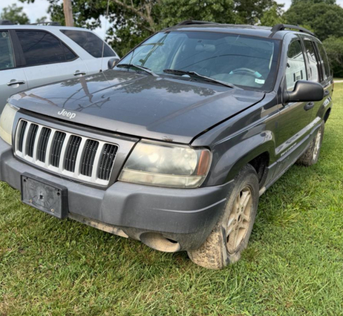 (1) DARK GRAY JEEP GRAND CHEROKEE LAREDO FOUR-DOOR SUV WITH AUTOMATIC TRANSMISSION, 4X4, ROOF RACK, TINTED REAR WINDOWS, ALLOY WHEELS, AND BLACK SEAT COVERS. VEHICLE SHOWS DIRT, CLOUDY HEADLIGHTS, EXTERIOR SCUFFS, MINOR BODY WEAR, AND A MISMATCHED STEEL F