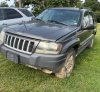 (1) DARK GRAY JEEP GRAND CHEROKEE LAREDO FOUR-DOOR SUV WITH AUTOMATIC TRANSMISSION, 4X4, ROOF RACK, TINTED REAR WINDOWS, ALLOY WHEELS, AND BLACK SEAT COVERS. VEHICLE SHOWS DIRT, CLOUDY HEADLIGHTS, EXTERIOR SCUFFS, MINOR BODY WEAR, AND A MISMATCHED STEEL F