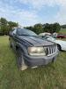 (1) DARK GRAY JEEP GRAND CHEROKEE LAREDO FOUR-DOOR SUV WITH AUTOMATIC TRANSMISSION, 4X4, ROOF RACK, TINTED REAR WINDOWS, ALLOY WHEELS, AND BLACK SEAT COVERS. VEHICLE SHOWS DIRT, CLOUDY HEADLIGHTS, EXTERIOR SCUFFS, MINOR BODY WEAR, AND A MISMATCHED STEEL F - 3