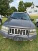 (1) DARK GRAY JEEP GRAND CHEROKEE LAREDO FOUR-DOOR SUV WITH AUTOMATIC TRANSMISSION, 4X4, ROOF RACK, TINTED REAR WINDOWS, ALLOY WHEELS, AND BLACK SEAT COVERS. VEHICLE SHOWS DIRT, CLOUDY HEADLIGHTS, EXTERIOR SCUFFS, MINOR BODY WEAR, AND A MISMATCHED STEEL F - 4