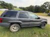 (1) DARK GRAY JEEP GRAND CHEROKEE LAREDO FOUR-DOOR SUV WITH AUTOMATIC TRANSMISSION, 4X4, ROOF RACK, TINTED REAR WINDOWS, ALLOY WHEELS, AND BLACK SEAT COVERS. VEHICLE SHOWS DIRT, CLOUDY HEADLIGHTS, EXTERIOR SCUFFS, MINOR BODY WEAR, AND A MISMATCHED STEEL F - 5