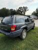 (1) DARK GRAY JEEP GRAND CHEROKEE LAREDO FOUR-DOOR SUV WITH AUTOMATIC TRANSMISSION, 4X4, ROOF RACK, TINTED REAR WINDOWS, ALLOY WHEELS, AND BLACK SEAT COVERS. VEHICLE SHOWS DIRT, CLOUDY HEADLIGHTS, EXTERIOR SCUFFS, MINOR BODY WEAR, AND A MISMATCHED STEEL F - 9