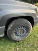 (1) DARK GRAY JEEP GRAND CHEROKEE LAREDO FOUR-DOOR SUV WITH AUTOMATIC TRANSMISSION, 4X4, ROOF RACK, TINTED REAR WINDOWS, ALLOY WHEELS, AND BLACK SEAT COVERS. VEHICLE SHOWS DIRT, CLOUDY HEADLIGHTS, EXTERIOR SCUFFS, MINOR BODY WEAR, AND A MISMATCHED STEEL F - 19
