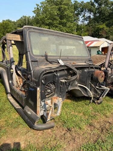 (1) BLACK JEEP WRANGLER 4.0L SPORT OFFERED AS A PROJECT, RESTORATION, OR PARTS VEHICLE. INCLUDES BODY TUB, WINDSHIELD FRAME AND GLASS, ROLL BAR ASSEMBLY, DAMAGED SOFT TOP, DASH COMPONENTS, STEERING WHEEL, BUMPERS, FENDER FLARES, SIDE STEPS, AND ASSORTED L
