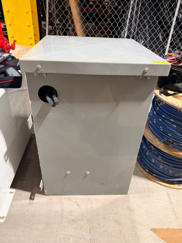 DRY-TYPE THREE-PHASE TRANSFORMER WITH VENTILATED STEEL ENCLOSURE, REMOVABLE ACCESS PANELS, AND MULTIPLE PRIMARY VOLTAGE TAP CONNECTIONS.
