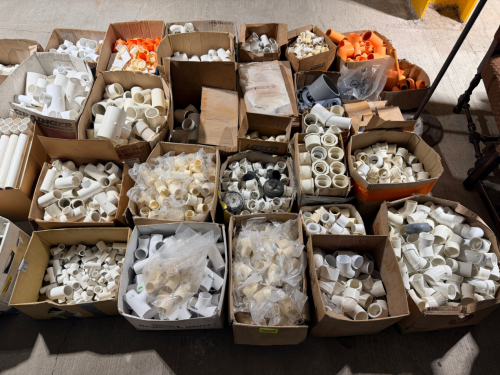 LARGE ASSORTED LOT OF PVC AND PLASTIC PIPE FITTINGS INCLUDING COUPLINGS, ELBOWS, TEES, REDUCERS, ADAPTERS, CAPS, BUSHINGS, AND OTHER MISCELLANEOUS FITTINGS IN VARIOUS SIZES. LOT CONSISTS PRIMARILY OF WHITE PVC FITTINGS WITH ADDITIONAL CREAM, GRAY, AND ORA