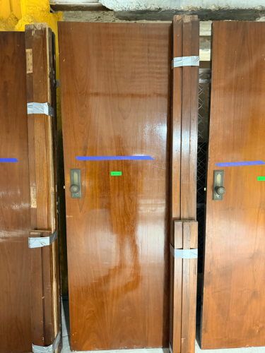 VINTAGE SOLID WOOD DOOR WITH DARK BROWN FINISH, CONTRASTING DECORATIVE INLAY, MATCHING WOOD TRIM COMPONENTS, AND PERIOD-STYLE METAL HARDWARE. DOOR FEATURES A RECTANGULAR RECESSED DECORATIVE BORDER, ROUND METAL KNOB, RECTANGULAR BACKPLATE, KEYHOLE, AND MOR