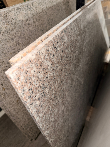 (2) PANEL GRANITE SHOWER SURROUND SET WITH POLISHED SPECKLED STONE SURFACES AND FINISHED EDGES. PANELS FEATURE A LIGHT GRAY, CREAM, PINK, AND BLACK NATURAL STONE PATTERN.