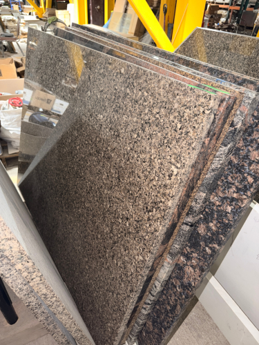 (2) GRANITE COUNTER TOP PIECES W/ POLISHED NATURAL STONE SURFACES FEATURING A DARK BROWN, BLACK, GRAY, AND TAN SPECKLED PATTERN.