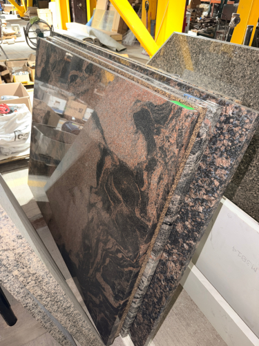 (4) GRANITE COUNTER TOP PIECES W/ POLISHED NATURAL STONE SURFACES FEATURING A BLACK, DARK BROWN, RUST, AND RED SWIRLED PATTERN.