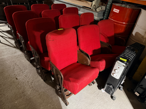 (12) RED UPHOLSTERED THEATER SEATS W/ METAL FRAMES AND SWING UP SEAT CUSHIONS.