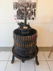 ANTIQUE WOODEN BASKET WINE / FRUIT PRESS WITH HEAVY CAST IRON FRAME, LARGE THREADED SCREW PRESS, CIRCULAR WOOD SLAT BASKET, STEEL BANDS, PRESSING PLATEN, AND CAST IRON THREE-LEG BASE. UNIT SHOWS HEAVY AGE-RELATED PATINA, SURFACE RUST, WOOD WEATHERING, AND