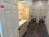 COMPLETE COMMERCIAL RESTROOM FIXTURE PACKAGE INCLUDING DOUBLE-SINK VANITY WITH SOLID SURFACE TOP, TWO INTEGRATED SINK BASINS, TWO FAUCETS, MIRROR, WALL-MOUNTED LIGHT FIXTURE, TWO WALL-MOUNTED URINALS, TWO TOILETS, TOILET/URINAL PARTITIONS, PAPER TOWEL DIS - 2
