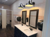 COMMERCIAL RESTROOM FIXTURE PACKAGE INCLUDING DOUBLE-SINK VANITY WITH WHITE SOLID SURFACE TOP, TWO UNDERMOUNT SINK BASINS, TWO BLACK FAUCETS, TWO FRAMED WALL MIRRORS, TWO BLACK WALL-MOUNTED LIGHT FIXTURES, TWO TOILETS, TOILET PARTITIONS, PAPER TOWEL DISPE - 2