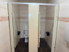 COMMERCIAL RESTROOM FIXTURE PACKAGE INCLUDING DOUBLE-SINK VANITY WITH WHITE SOLID SURFACE TOP, TWO UNDERMOUNT SINK BASINS, TWO BLACK FAUCETS, TWO FRAMED WALL MIRRORS, TWO BLACK WALL-MOUNTED LIGHT FIXTURES, TWO TOILETS, TOILET PARTITIONS, PAPER TOWEL DISPE - 7