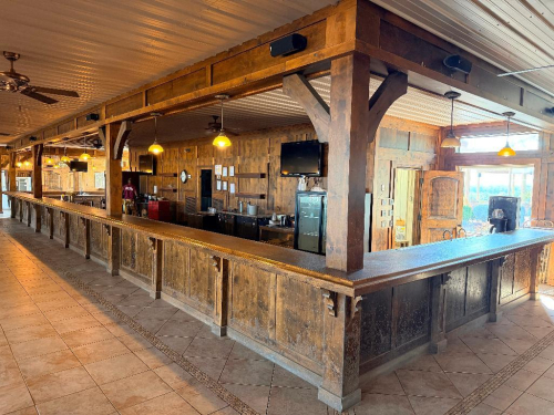 60'X 14' " U " SHAPED CUSTOM-BUILT U-SHAPED COMMERCIAL BAR WITH RUSTIC WOOD CONSTRUCTION, RAISED BAR TOP, LOWER WORK COUNTERS, EXTENSIVE BASE CABINETRY, DRAWERS, STORAGE COMPARTMENTS, DECORATIVE WOOD PANELS, HEAVY TIMBER POSTS, OVERHEAD WOOD BEAM/CANOPY S