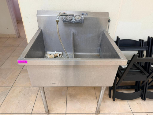 STAINLESS STEEL TWO-COMPARTMENT SINK WITH DEEP BASINS, INTEGRAL BACKSPLASH, DECK-MOUNTED FAUCET ASSEMBLY WITH FLEXIBLE SPRAY HOSE, DRAIN FITTINGS, AND FOUR STAINLESS STEEL LEGS.