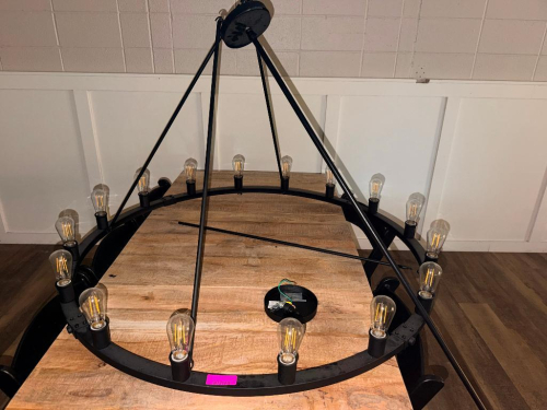 LARGE ROUND BLACK METAL RING CHANDELIER WITH EXPOSED EDISON-STYLE BULBS, SUSPENDED BY MULTIPLE METAL SUPPORT RODS TO A ROUND CEILING CANOPY. FIXTURE INCLUDES APPROXIMATELY (16) INDIVIDUAL LIGHT SOCKETS AND BULBS.