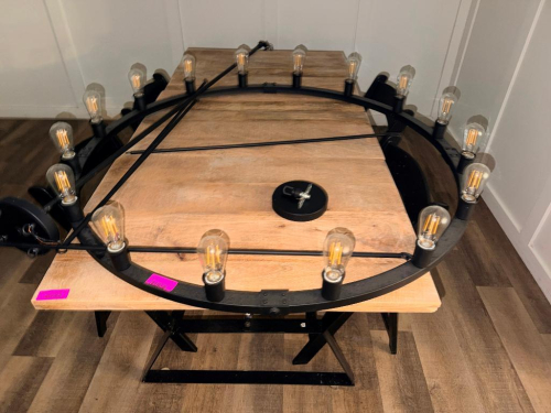 LARGE ROUND BLACK METAL RING CHANDELIER WITH EXPOSED EDISON-STYLE BULBS, SUSPENDED BY MULTIPLE METAL SUPPORT RODS TO A ROUND CEILING CANOPY. FIXTURE INCLUDES APPROXIMATELY (16) INDIVIDUAL LIGHT SOCKETS AND BULBS.