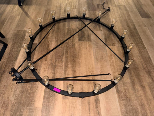 LARGE ROUND BLACK METAL RING CHANDELIER WITH EXPOSED EDISON-STYLE BULBS, SUSPENDED BY MULTIPLE METAL SUPPORT RODS TO A ROUND CEILING CANOPY. FIXTURE INCLUDES APPROXIMATELY (16) INDIVIDUAL LIGHT SOCKETS AND BULBS.
