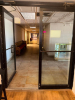 COMMERCIAL DOUBLE GLASS ENTRY DOOR ASSEMBLY WITH BLACK METAL FRAME, FULL-LENGTH GLASS PANELS, PUSH/PULL HARDWARE, OVERHEAD DOOR CLOSERS, AND THRESHOLD.