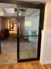 COMMERCIAL DOUBLE GLASS ENTRY DOOR ASSEMBLY WITH BLACK METAL FRAME, FULL-LENGTH GLASS PANELS, PUSH/PULL HARDWARE, OVERHEAD DOOR CLOSERS, AND THRESHOLD. - 2