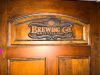 72" WIDE X 80"SOLID WOOD PANEL DOUBLE DOOR WITH DARK STAINED FINISH AND DECORATIVE ROUTED/RAISED PANELS. FEATURES CUSTOM &ldquo;BREWING CO. & DISTILLING&rdquo; GRAPHIC, WHEAT/BARLEY, TRACTOR, BUILDING, AND STATE-SHAPED DECORATIVE DESIGNS INSET INTO THE DOOR. HEAVY-DU - 4