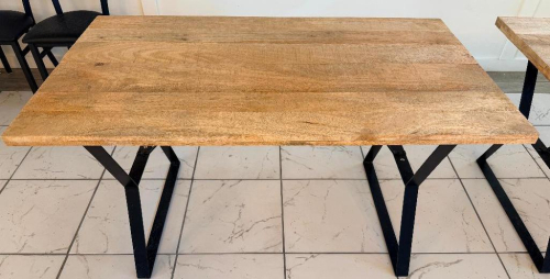 55" X 32" SOLID WOOD DINING / COMMUNITY TABLE WITH WIDE PLANK TOP AND BLACK METAL TRESTLE-STYLE LEGS. NATURAL WOOD TOP FEATURES VISIBLE GRAIN, KNOTS, COLOR VARIATION, AND A LIGHTLY DISTRESSED/RUSTIC FINISH.