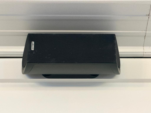 (10) WALL-MOUNTED POLK AUDIO LOUDSPEAKER WITH BLACK ENCLOSURE, CURVED FRONT GRILLE, AND WALL-MOUNT INSTALLATION.
