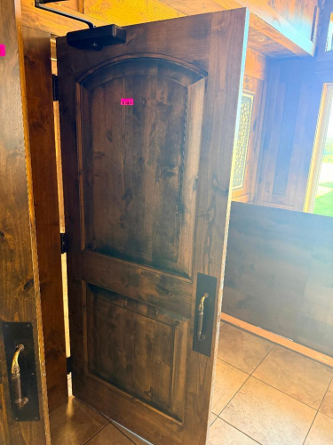 SOLID CORE WOOD DOOR WITH STAINED FINISH, ARCHED RAISED PANEL DESIGN, HEAVY-DUTY HINGES, METAL PULL HANDLE, AND OVERHEAD HYDRAULIC DOOR CLOSER.