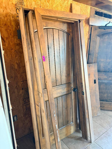 SOLID CORE WOOD DOOR WITH STAINED FINISH, ARCHED RAISED PANEL DESIGN, HEAVY-DUTY HINGES, METAL PULL HANDLE, AND OVERHEAD HYDRAULIC DOOR CLOSER.