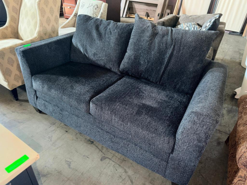 CHARCOAL GRAY UPHOLSTERED TWO-SEAT SOFA WITH TEXTURED FABRIC, TWO REMOVABLE SEAT CUSHIONS, TWO LARGE LOOSE BACK CUSHIONS, TWO ACCENT PILLOWS, WIDE PADDED ARMS, AND SHORT DARK FINISHED LEGS.