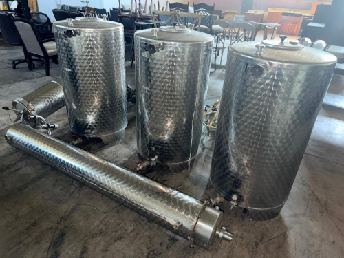 (3) STAINLESS STEEL VARIABLE-CAPACITY STORAGE / PROCESSING TANKS WITH (2) ADDITIONAL STAINLESS STEEL CYLINDRICAL VESSEL ASSEMBLIES. MAIN TANKS FEATURE DIMPLED / DECORATIVE STAINLESS EXTERIORS, REMOVABLE TOP LIDS, MULTIPLE SANITARY PORTS, BOTTOM OUTLET VAL
