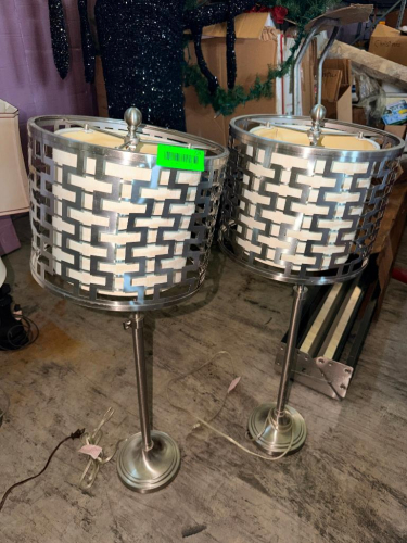 (2) MATCHING DECORATIVE TABLE LAMPS WITH BRUSHED NICKEL-TONE FINISH, ROUND PEDESTAL BASES, TALL COLUMN STEMS, CYLINDRICAL FABRIC SHADES, AND GEOMETRIC OPEN-METAL SHADE OVERLAYS.
