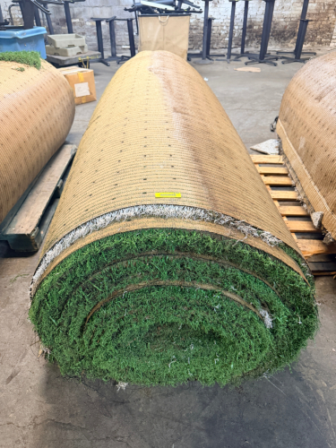 7.5' W X 40' L ARTIFICIAL TURF / ASTROTURF WITH GREEN SYNTHETIC GRASS SURFACE AND WOVEN BACKING. TURF IS ROLLED FOR STORAGE AND SHOWS VISIBLE DIRT, WEAR, FRAYING, AND RESIDUE CONSISTENT WITH PREVIOUS INSTALLATION AND REMOVAL.