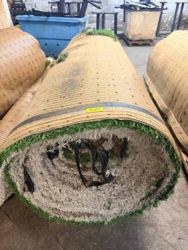 7.5' W X 40' L ARTIFICIAL TURF / ASTROTURF WITH GREEN SYNTHETIC GRASS SURFACE AND WOVEN BACKING. TURF IS ROLLED FOR STORAGE AND SHOWS VISIBLE DIRT, WEAR, FRAYING, AND RESIDUE CONSISTENT WITH PREVIOUS INSTALLATION AND REMOVAL.