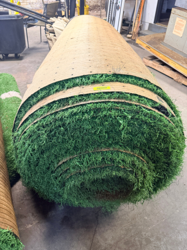7.5' W X 40' L ARTIFICIAL TURF / ASTROTURF WITH GREEN SYNTHETIC GRASS SURFACE AND WOVEN BACKING. TURF IS ROLLED FOR STORAGE AND SHOWS VISIBLE DIRT, WEAR, FRAYING, AND RESIDUE CONSISTENT WITH PREVIOUS INSTALLATION AND REMOVAL.