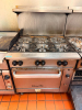 VULCAN COMMERCIAL SIX-BURNER NATURAL GAS RANGE WITH STANDARD OVEN BASE, HEAVY-DUTY CAST IRON OPEN-TOP GRATES, INDIVIDUAL BURNER CONTROLS, STAINLESS STEEL FRONT, BACKSPLASH, OVEN RACK, AND CASTERS.