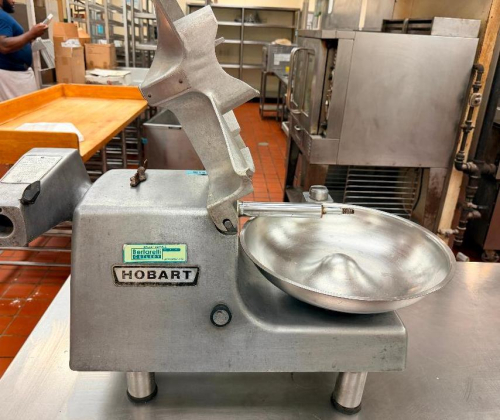 HOBART COMMERCIAL FOOD CUTTER / BUFFALO CHOPPER WITH CAST METAL BODY, STAINLESS STEEL BOWL, HINGED PRODUCT COVER, AND INTEGRATED MOTOR.