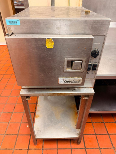 CLEVELAND STEAMCRAFT COMMERCIAL COUNTERTOP STEAMER WITH STAINLESS STEEL CABINET, FRONT-HINGED DOOR, MULTIPLE INTERIOR PAN RACK POSITIONS, MANUAL/TIMED CONTROLS, AND STAINLESS STEEL EQUIPMENT STAND WITH LOWER SHELF.