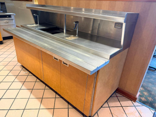84" WIDE X 38" CUSTOM STAINLESS STEEL COMMERCIAL BEVERAGE / SERVICE STATION WITH TWO INTEGRATED DRAIN BASINS WITH REMOVABLE GRATES, TWO WATER DISPENSING FAUCETS, CENTER EQUIPMENT OPENING, STAINLESS STEEL BACKSPLASH, UPPER OVER SHELF, AND RIBBED FRONT WORK
