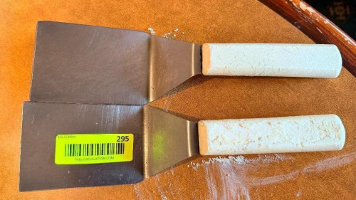 (2) STAINLESS SERVERS W/ WHITE PLASTIC HANDLES.