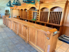 24' LONG CUSTOM-BUILT SOLID OAK BAR AND BACK BAR ASSEMBLY WITH RAISED-PANEL CABINETRY, DECORATIVE MOLDING, CARVED ACCENTS, ARCHED BACK-BAR SECTIONS, MULTIPLE WINE BOTTLE STORAGE CUBBIES, OPEN SHELVING, LOWER STORAGE COMPARTMENTS, SERVICE COUNTER, AND TRIP - 2
