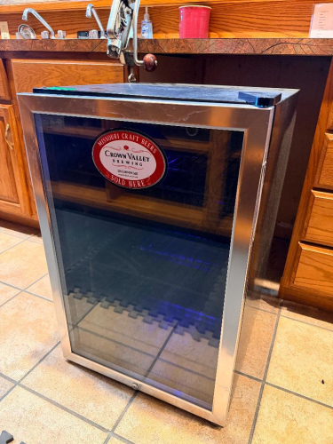 HAIER SINGLE-DOOR BEVERAGE CENTER WITH BLACK CABINET, STAINLESS STEEL DOOR FRAME, TINTED GLASS DOOR, ADJUSTABLE WIRE SHELVING, INTERIOR LIGHTING, AND MANUAL TEMPERATURE CONTROL.
