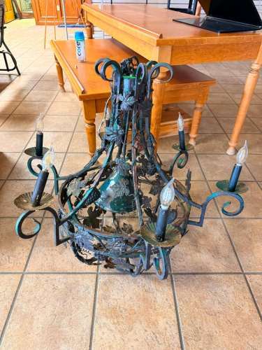 DECORATIVE WROUGHT IRON CHANDELIER WITH GRAPE LEAF AND GRAPE CLUSTER MOTIF, SCROLLED METAL ARMS, CENTRAL BELL-SHAPED BODY AND SIX CANDLE-STYLE LIGHT SOCKETS.