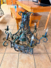 DECORATIVE WROUGHT IRON CHANDELIER WITH GRAPE LEAF AND GRAPE CLUSTER MOTIF, SCROLLED METAL ARMS, CENTRAL BELL-SHAPED BODY AND SIX CANDLE-STYLE LIGHT SOCKETS.