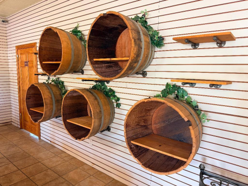 (5) WALL-MOUNTED HALF-BARREL DISPLAY SHELVES CONSTRUCTED FROM WOOD BARRELS WITH METAL HOOPS. EACH BARREL HAS AN OPEN FRONT WITH WOOD INTERIOR DISPLAY SHELF. INCLUDES WALL-MOUNTING HARDWARE